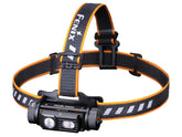 Fenix headlamp with orange and black strap on a white background
